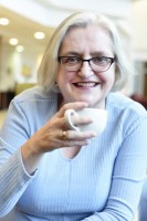 Heidi in a blue top with a cup of coffee